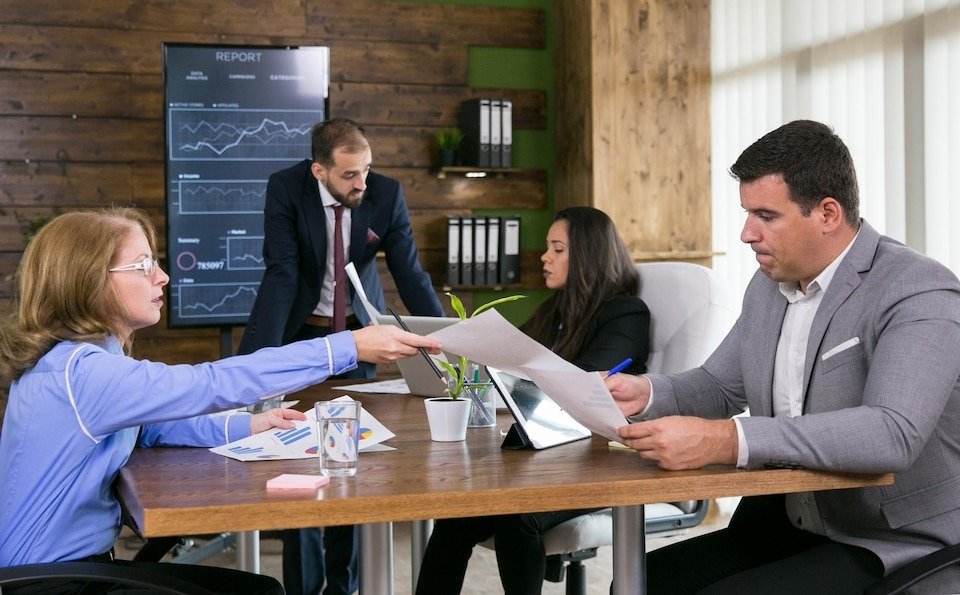 middle-age-business-woman-giving-charts-her-young-colleague-conference-room