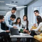 guy-shows-document-girl-group-young-freelancers-office-have-conversation-working-min-scaled